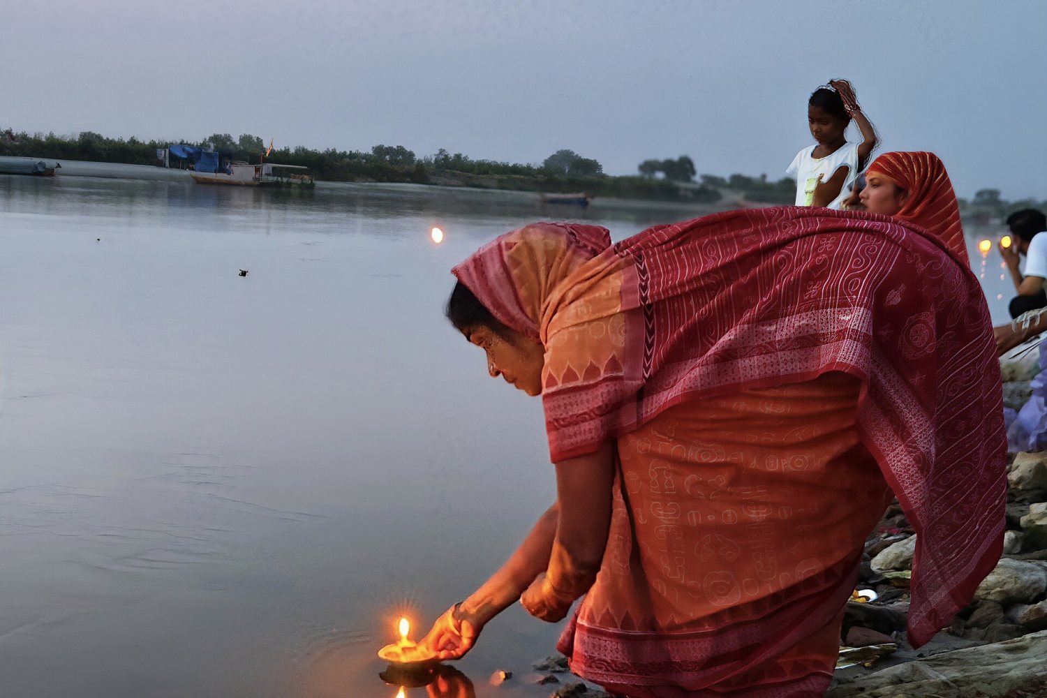 A woman floating a diya on the Yamuna at Keshi Ghat at dusk