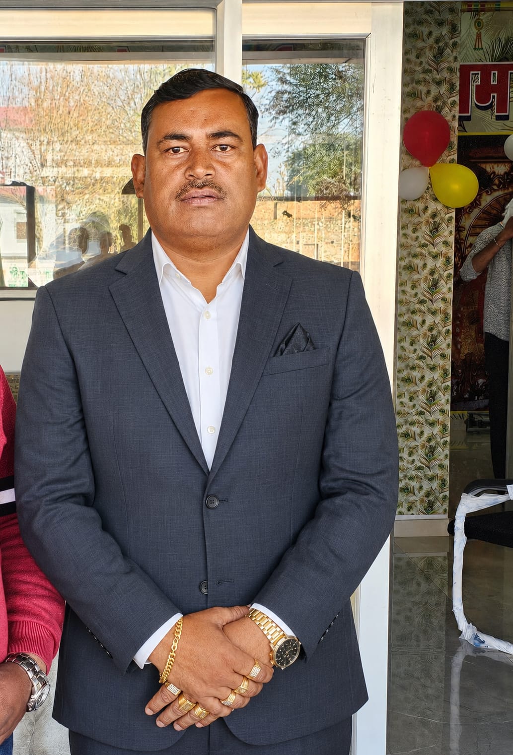 Rakesh Giri, founder of Sai Ram Developers, photographed outside the office in a grey suit.